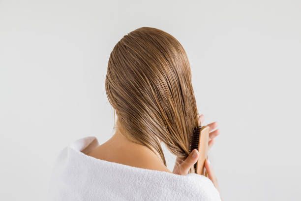 Eine Frau ist in ein weißes Handtuch gehüllt und hält ihr Haar.