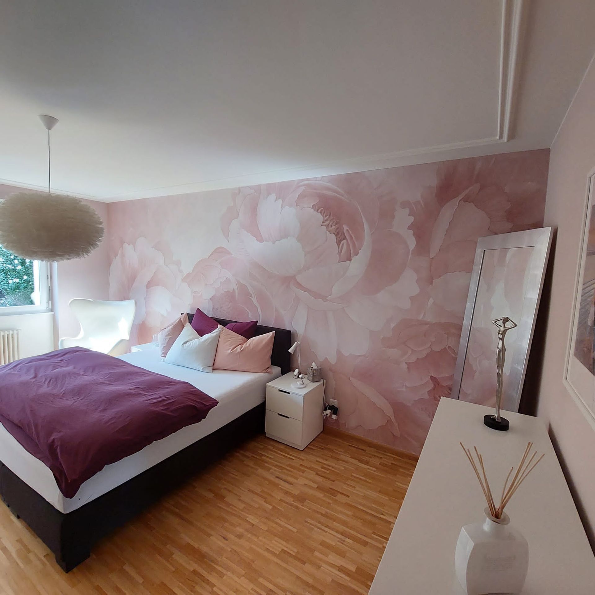 Ein Schlafzimmer mit Bett, Nachttisch und Spiegel