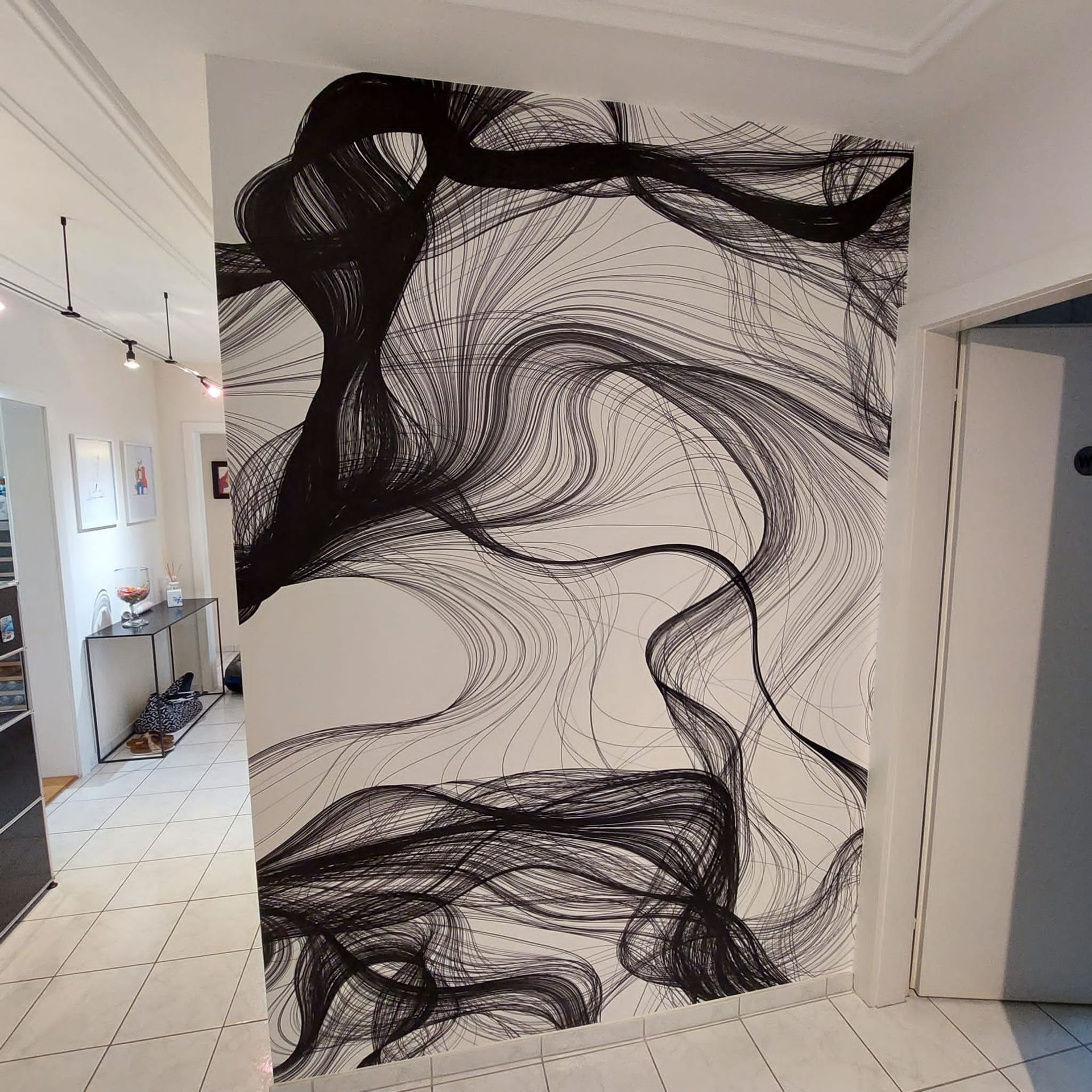 Ein Flur mit einem großen schwarz-weißen Gemälde an der Wand