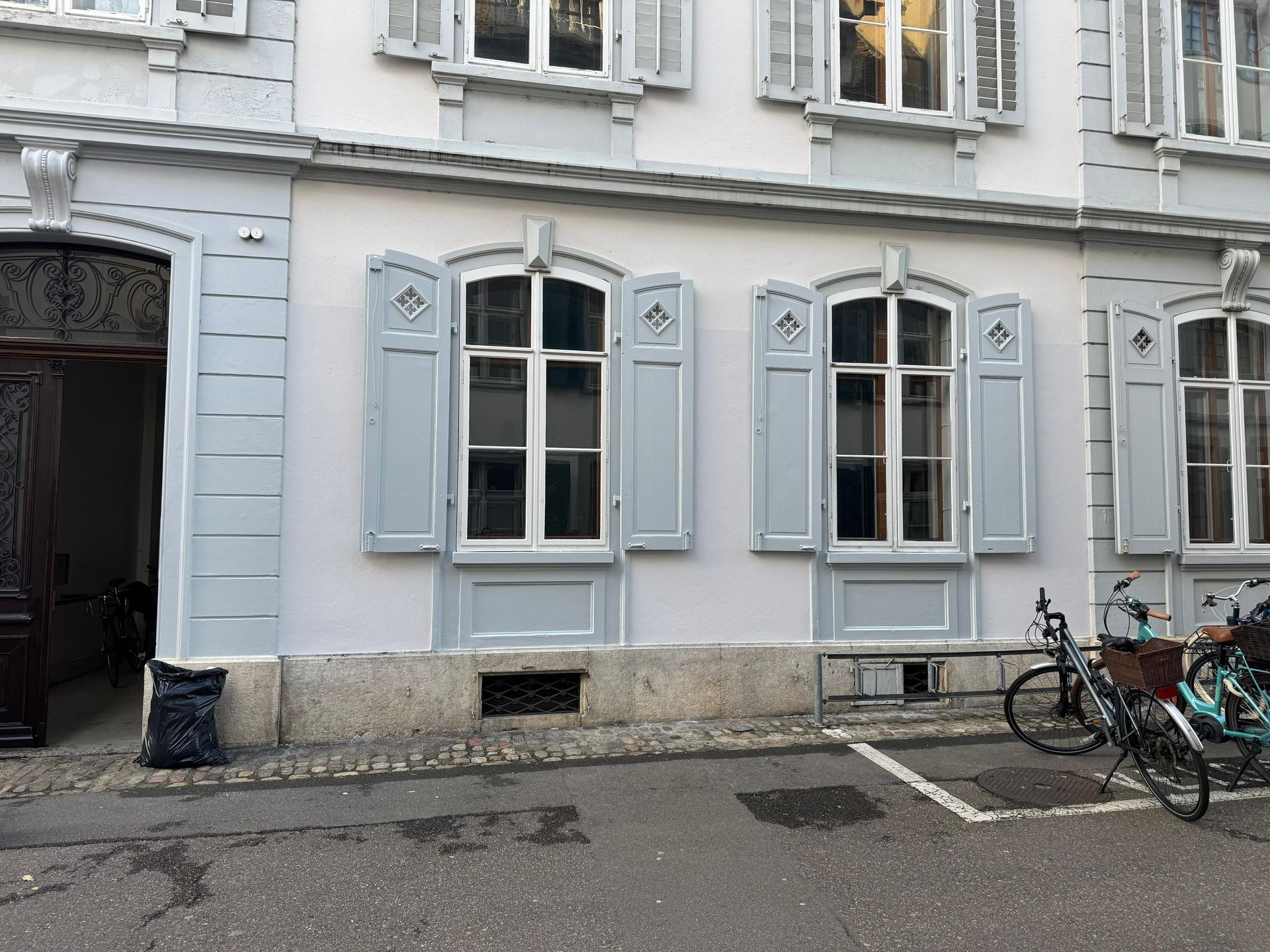 Vor einem Gebäude mit Fensterläden stehen zwei Fahrräder.