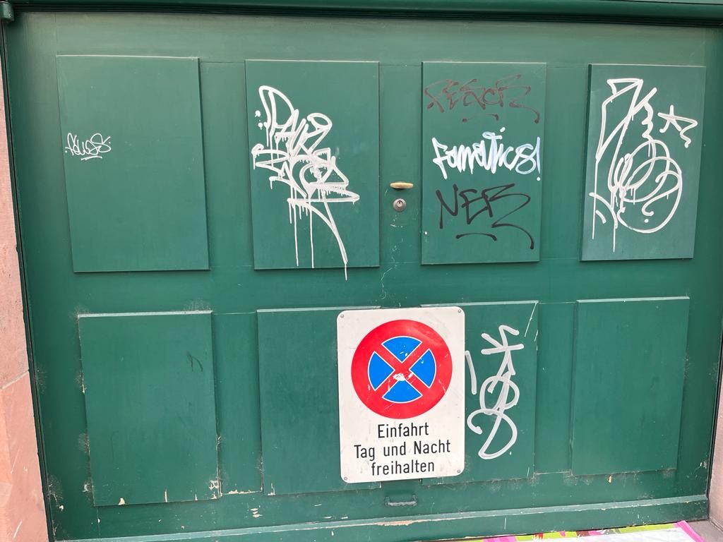 Eine grüne Tür mit Graffiti darauf und einem Parkverbotsschild