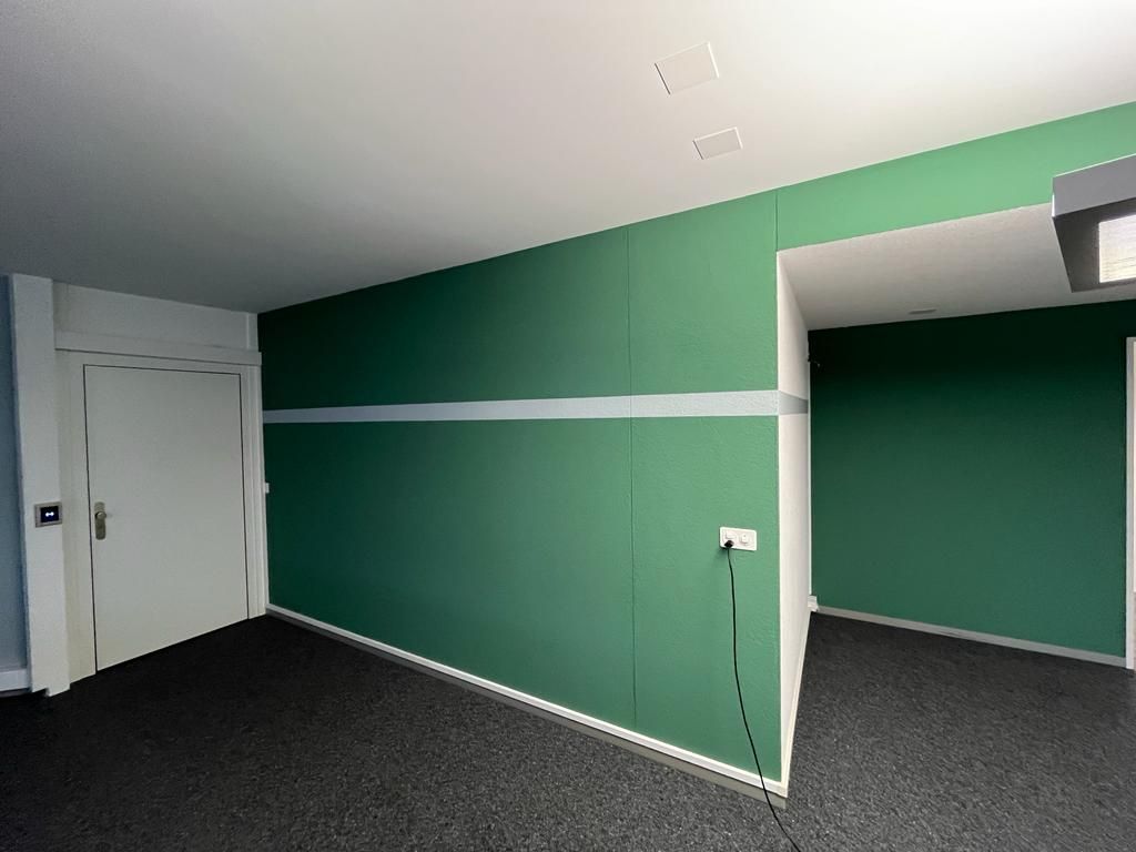 Ein leerer Raum mit grünen Wänden und schwarzem Teppich