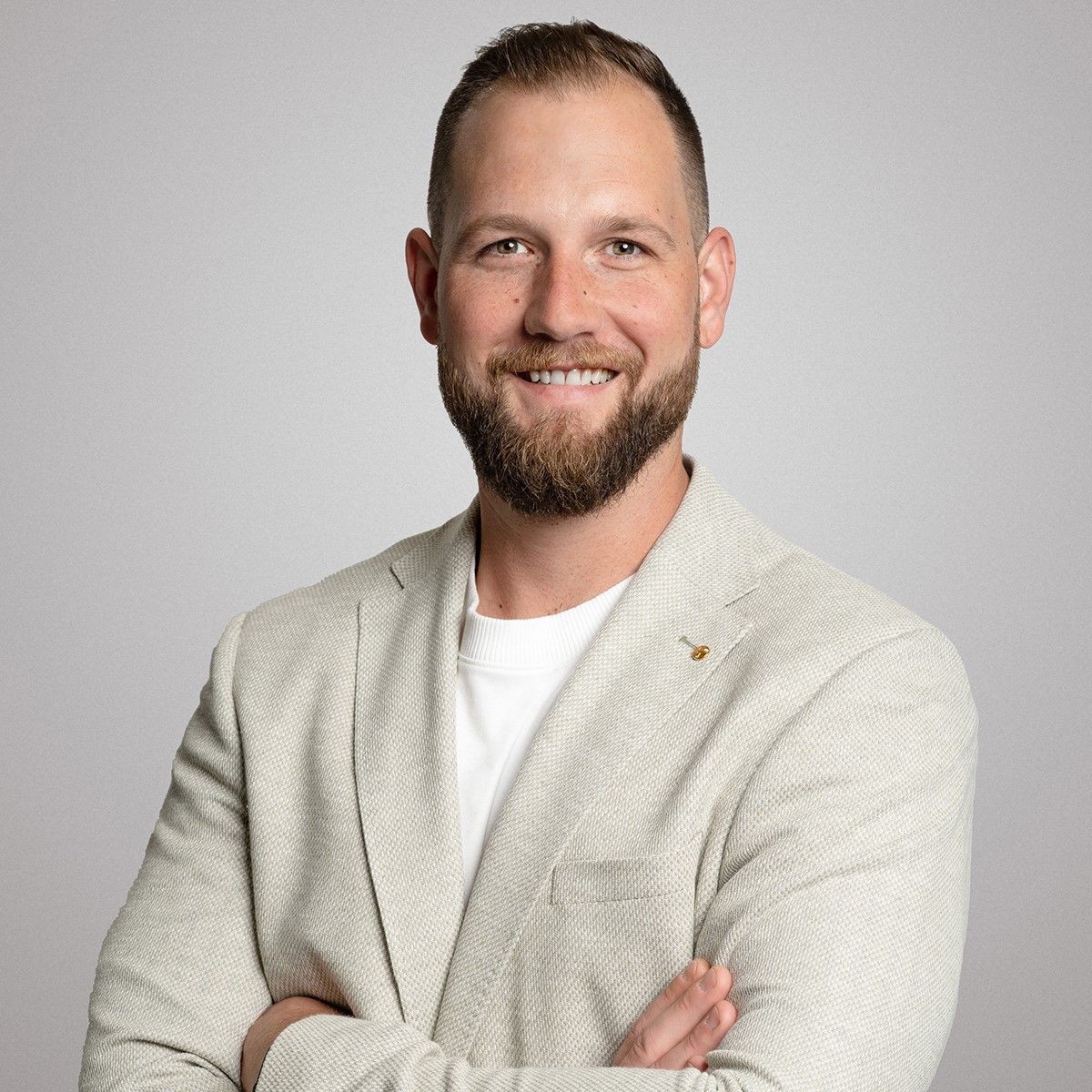 Ein Mann mit einem grauen Kapuzenpullover lächelt in die Kamera.
