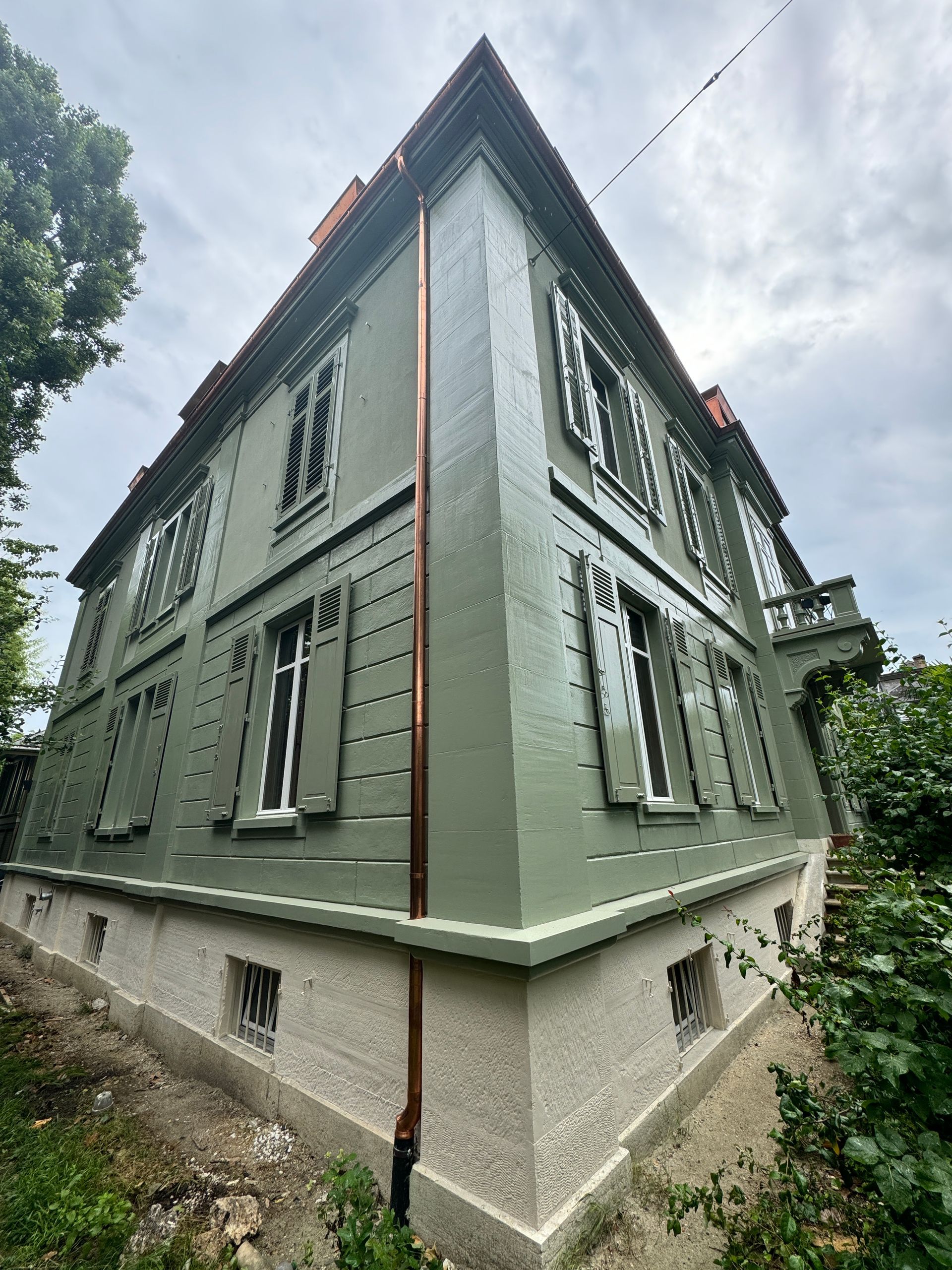 Ein großes grünes Gebäude mit einem Kupferrohr an der Seite.