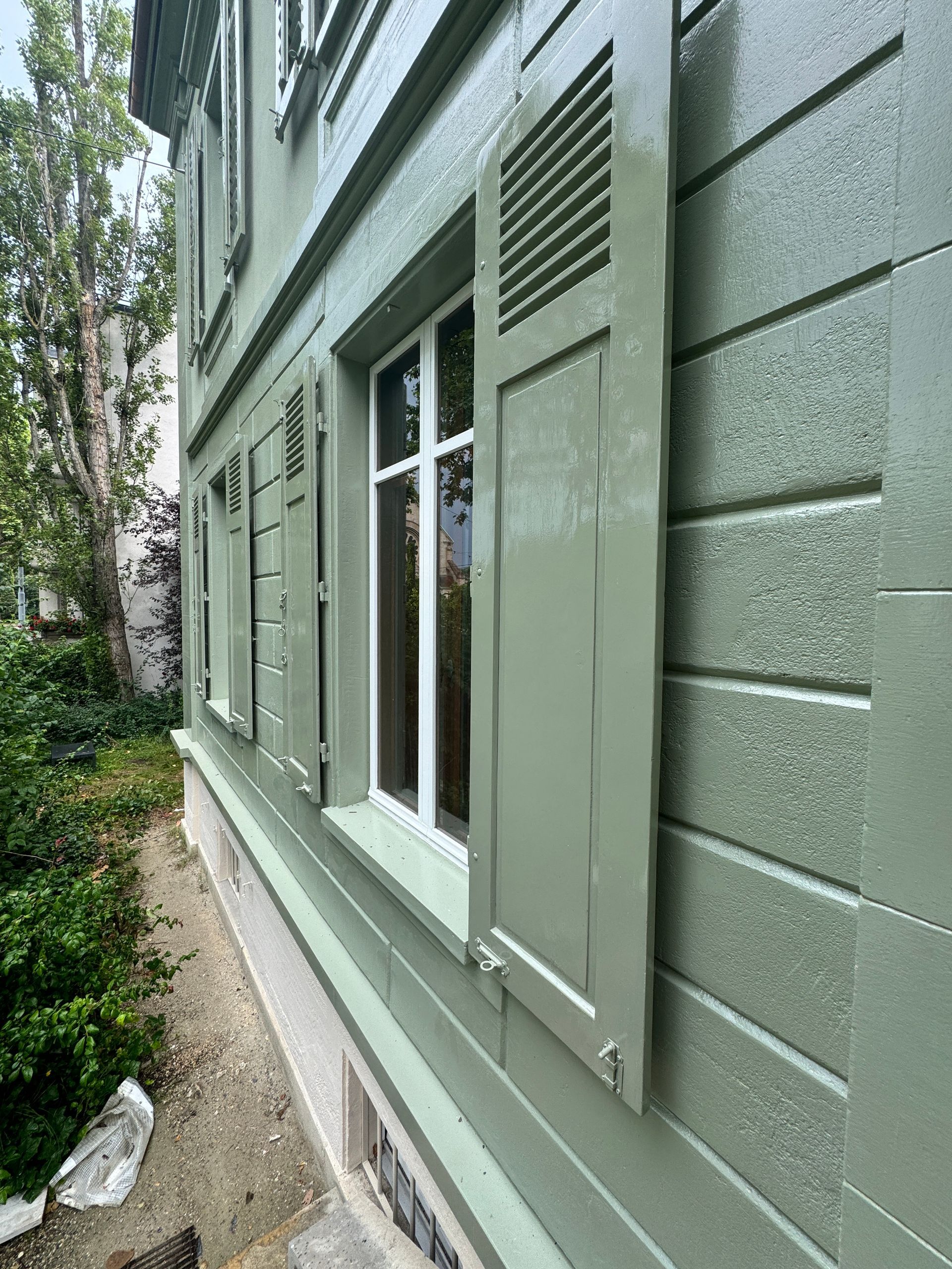 Ein grünes Gebäude mit weißen Fensterläden.