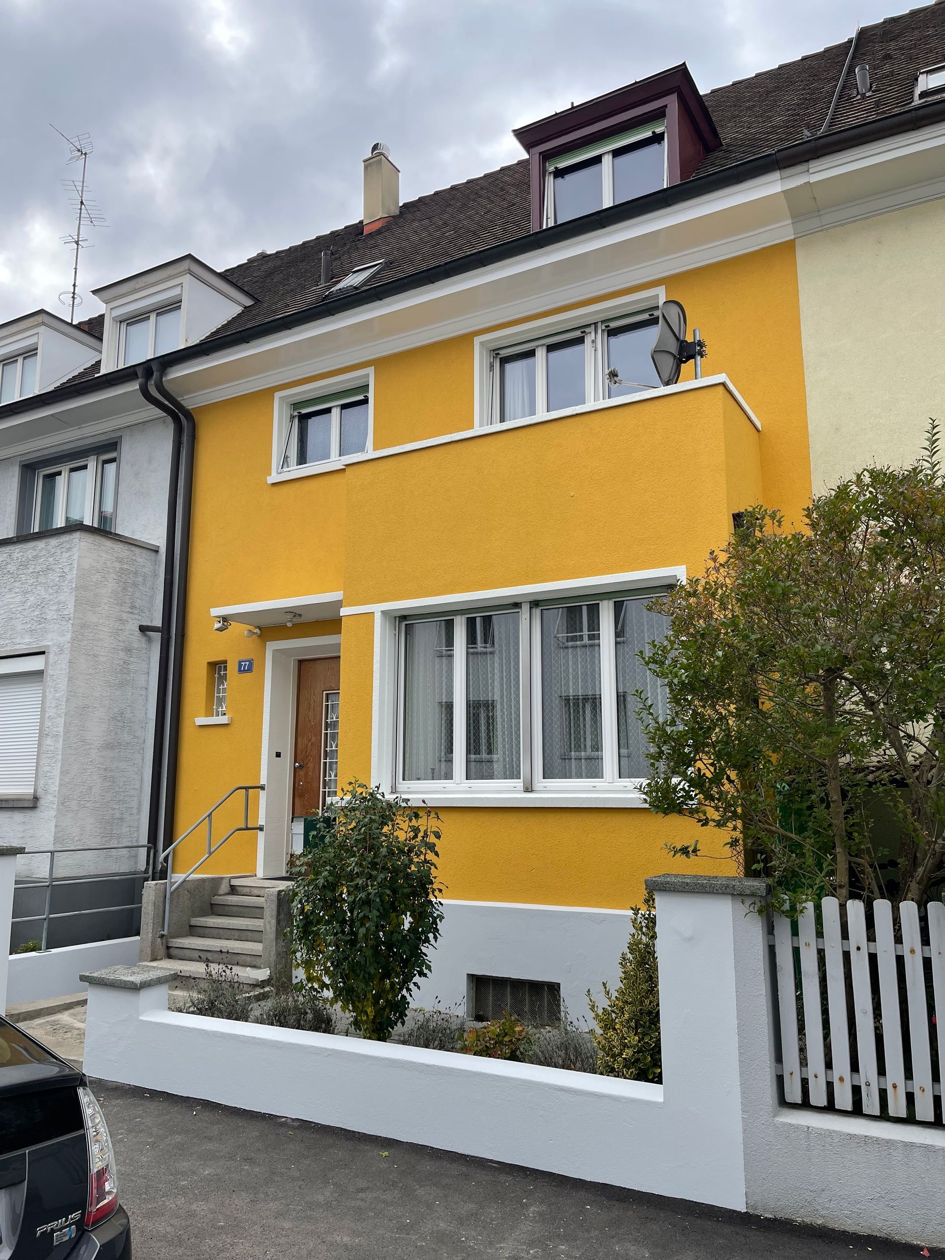 Ein gelbes Haus mit einem weißen Zaun davor