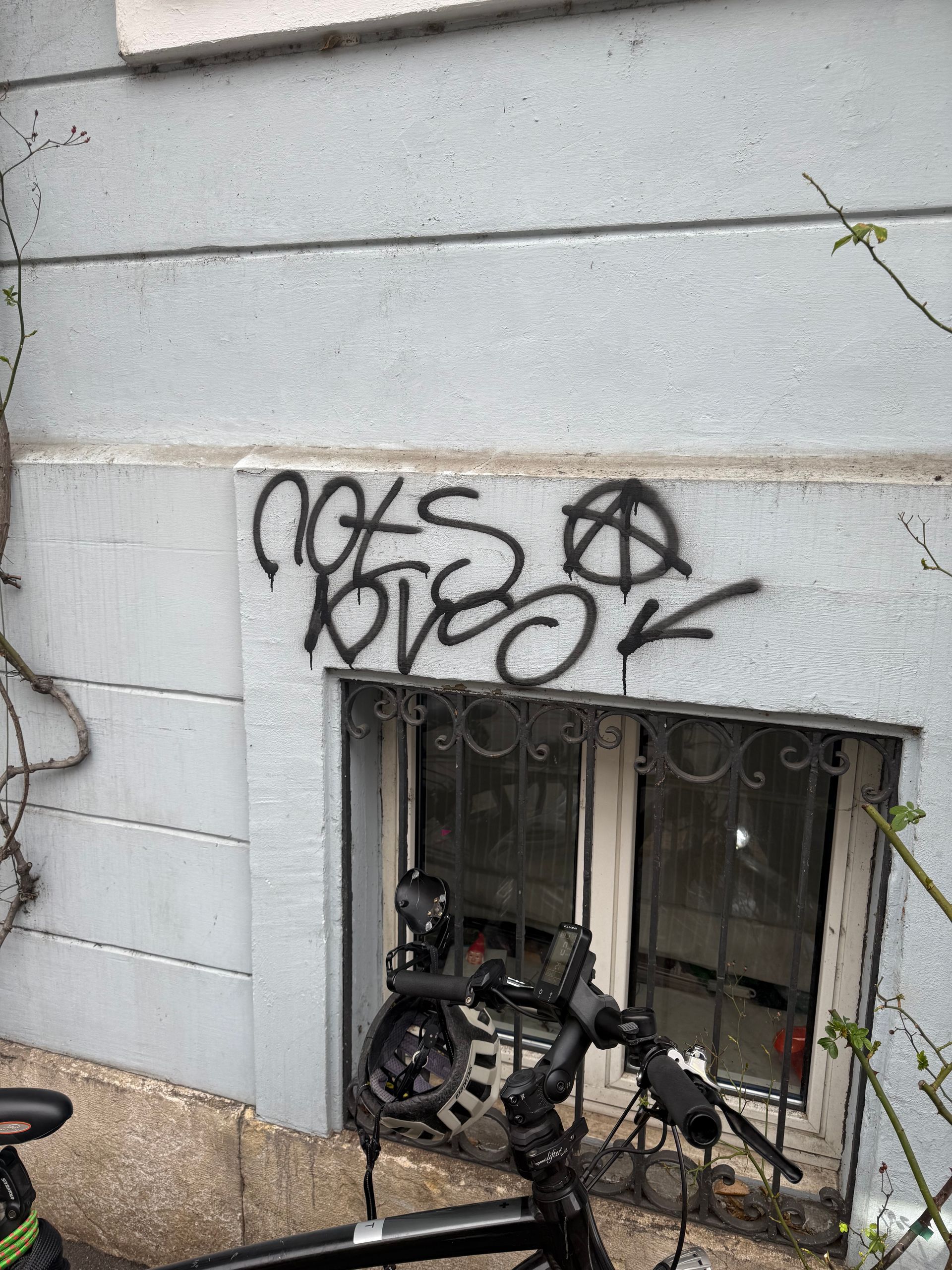 Vor einem Gebäude mit Graffiti steht ein Fahrrad.