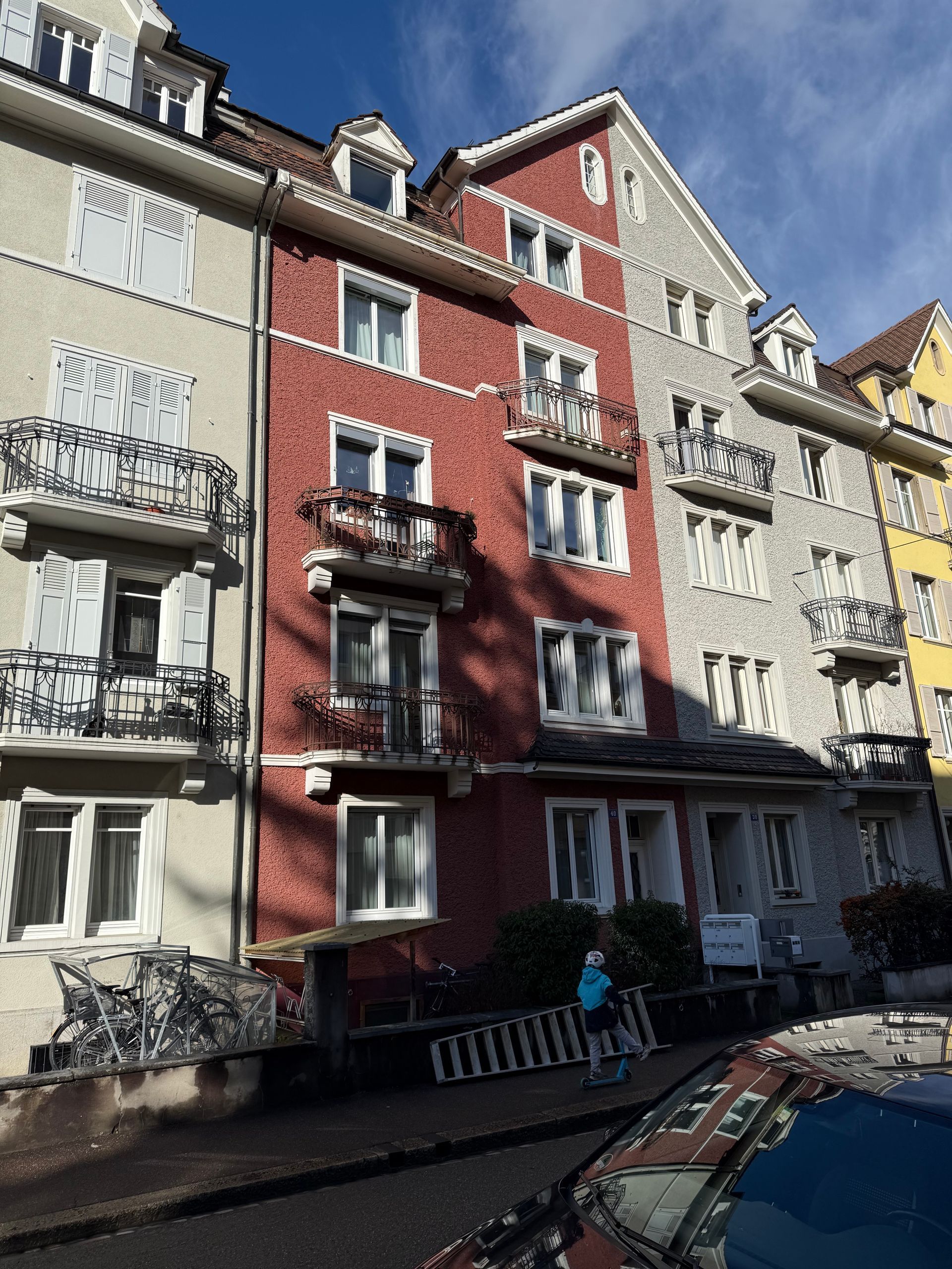 Ein rot-weißes Gebäude mit einem davor geparkten Auto.