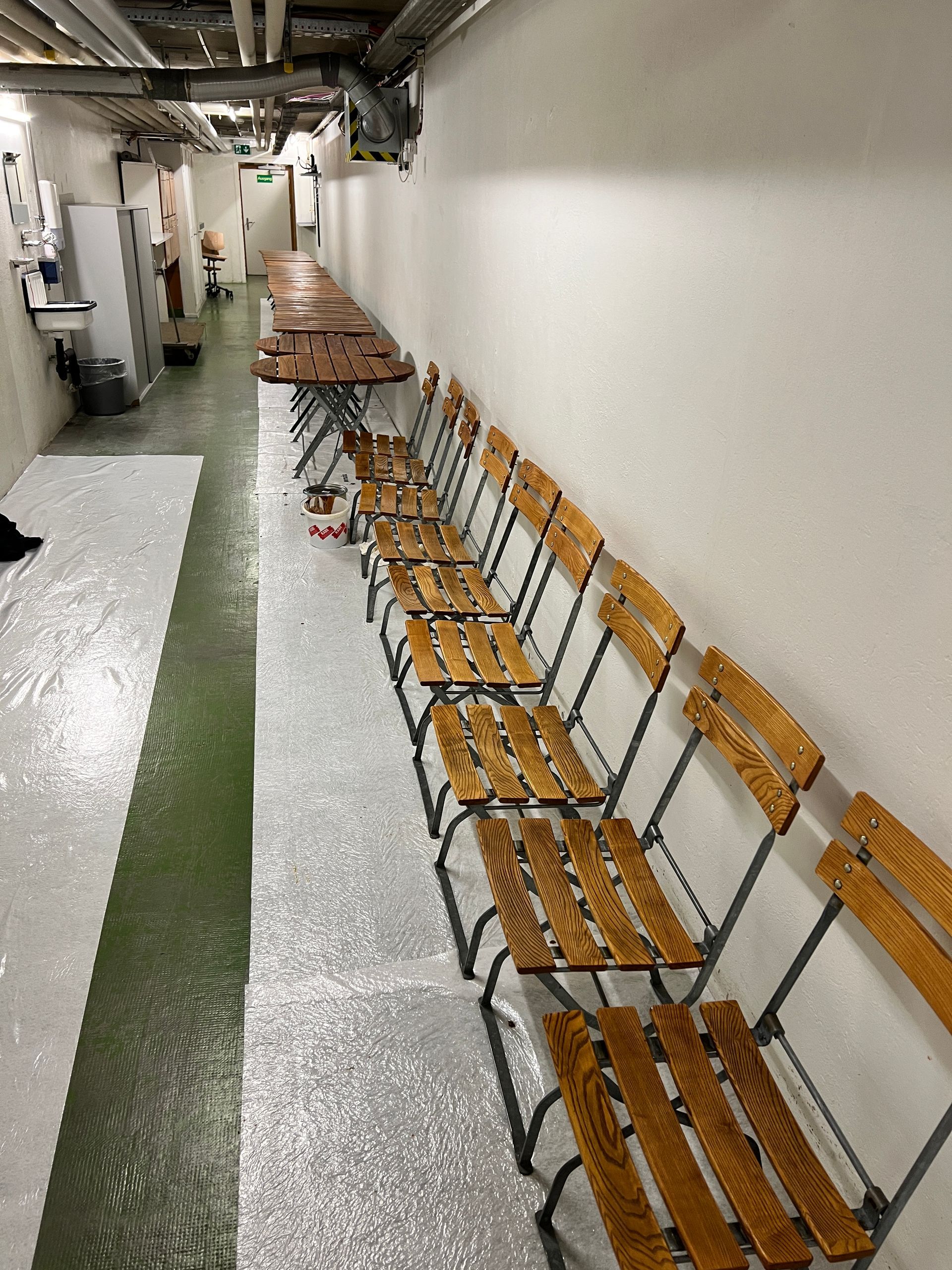 Ein langer Flur mit Holzstühlen und Tischen