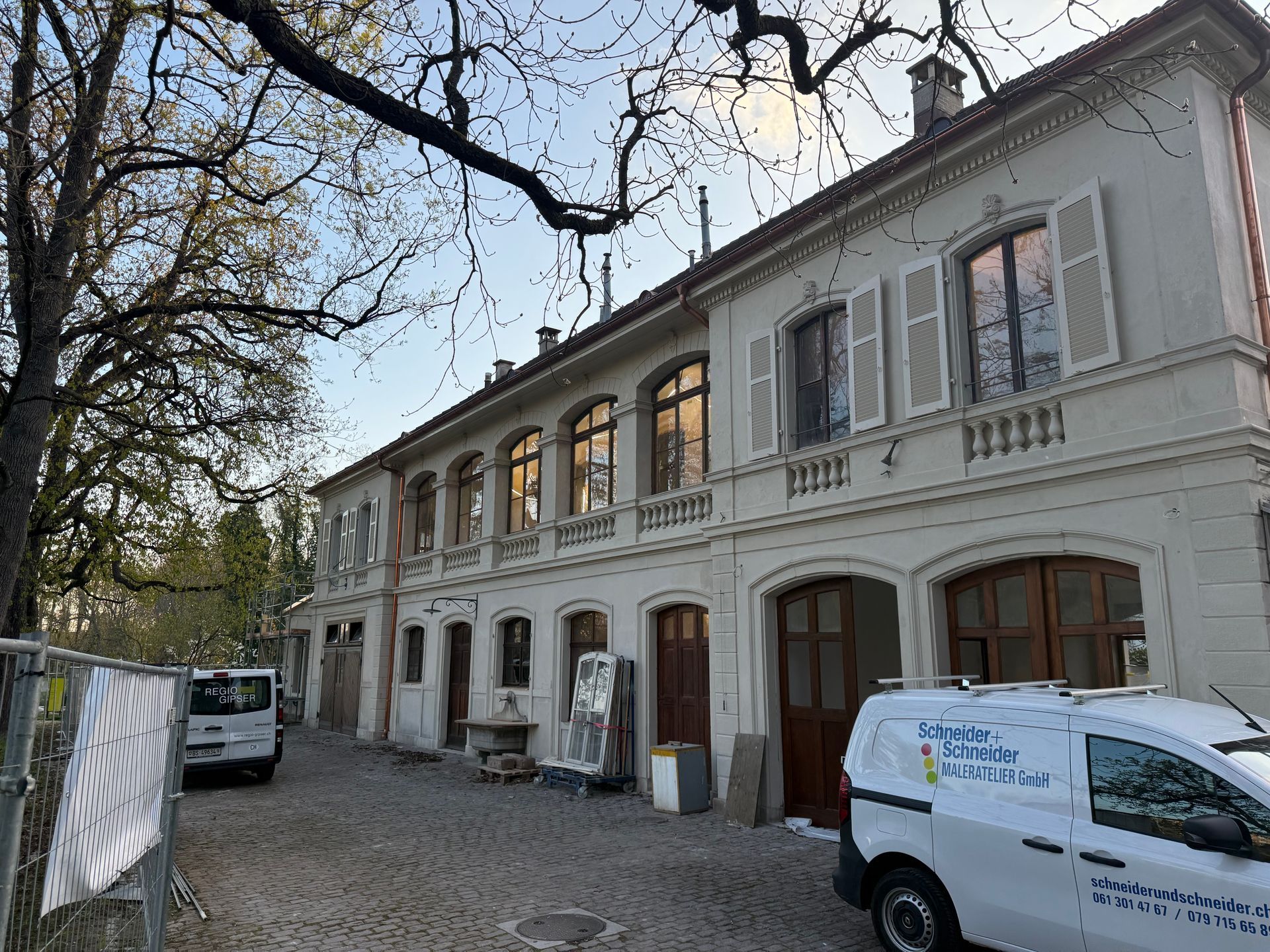 Ein weißer Lieferwagen parkt vor einem großen Gebäude.