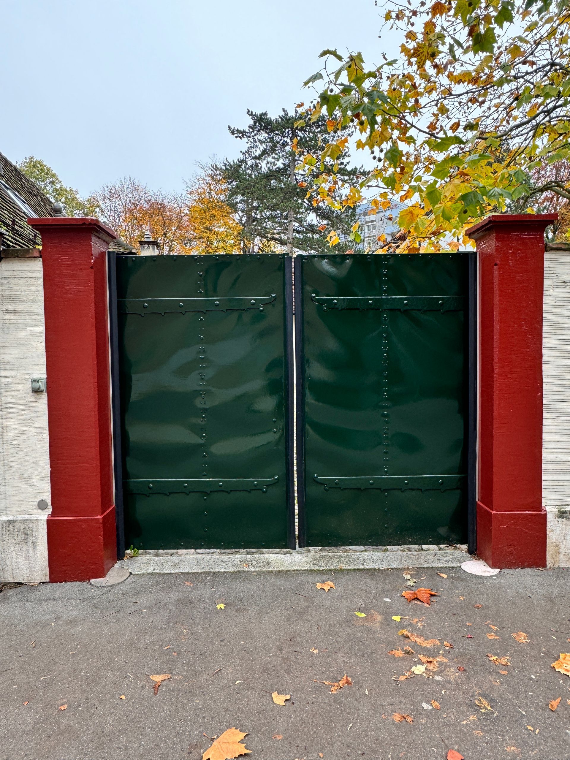 Ein grünes Tor ist von roten Säulen umgeben.