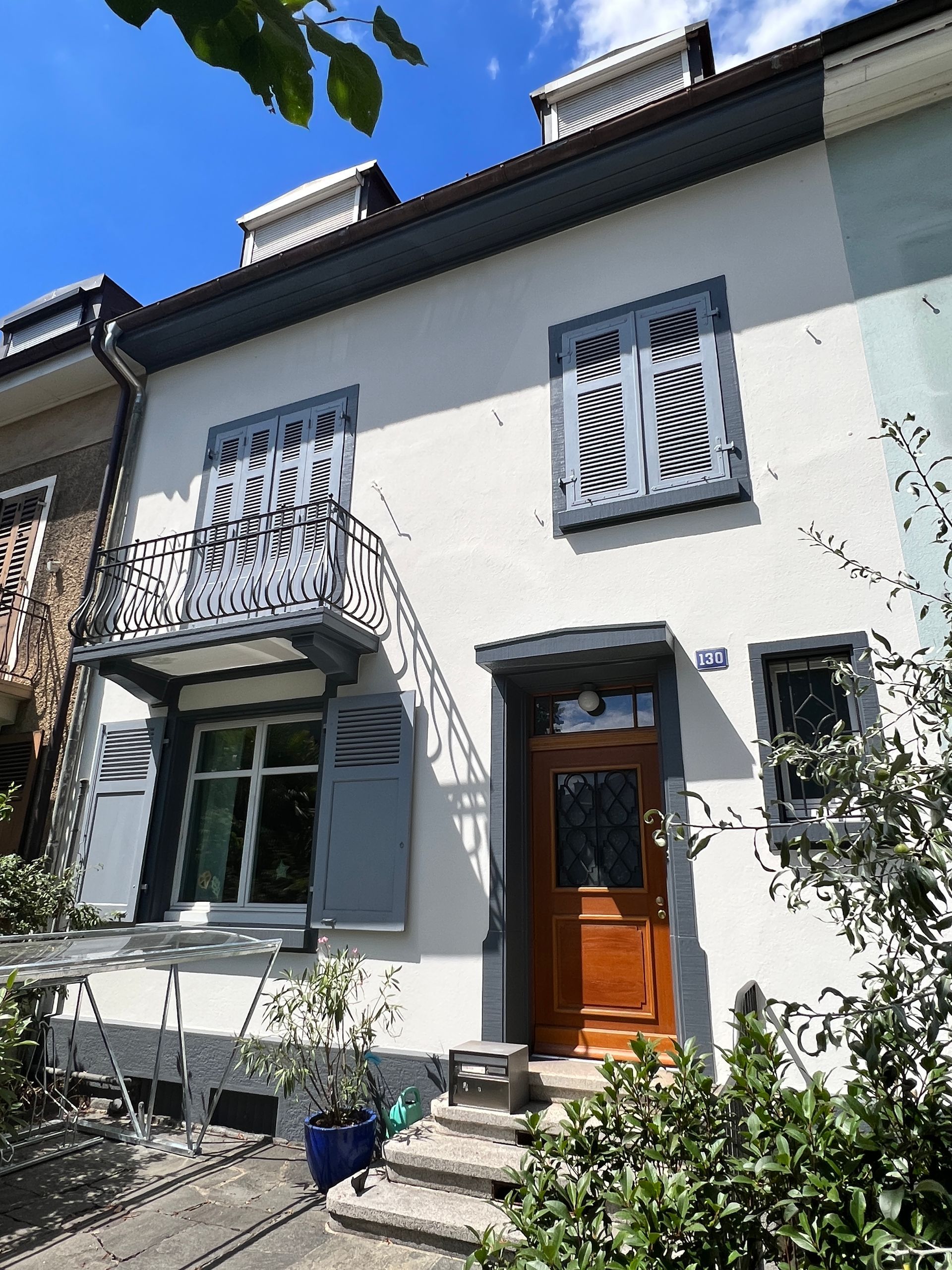 Ein weißes Haus mit einem Balkon und einer Holztür