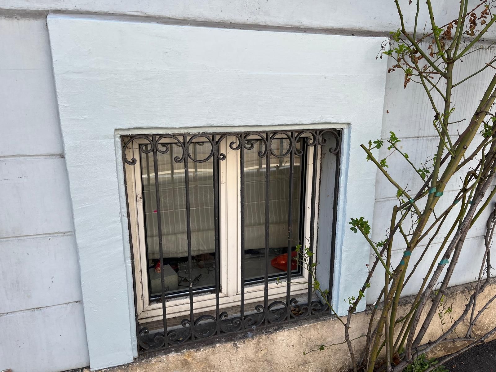 An der Seite eines Gebäudes befindet sich ein vergittertes Fenster.