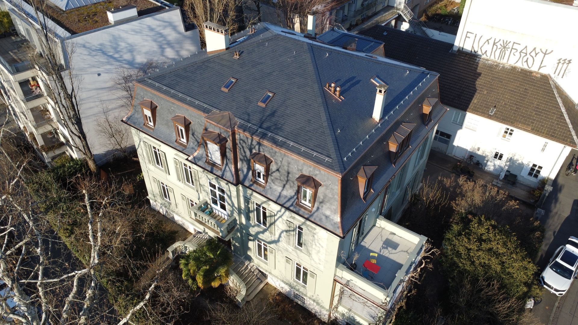 Eine Luftaufnahme eines großen Gebäudes mit einem mit Schindeln gedeckten Dach.