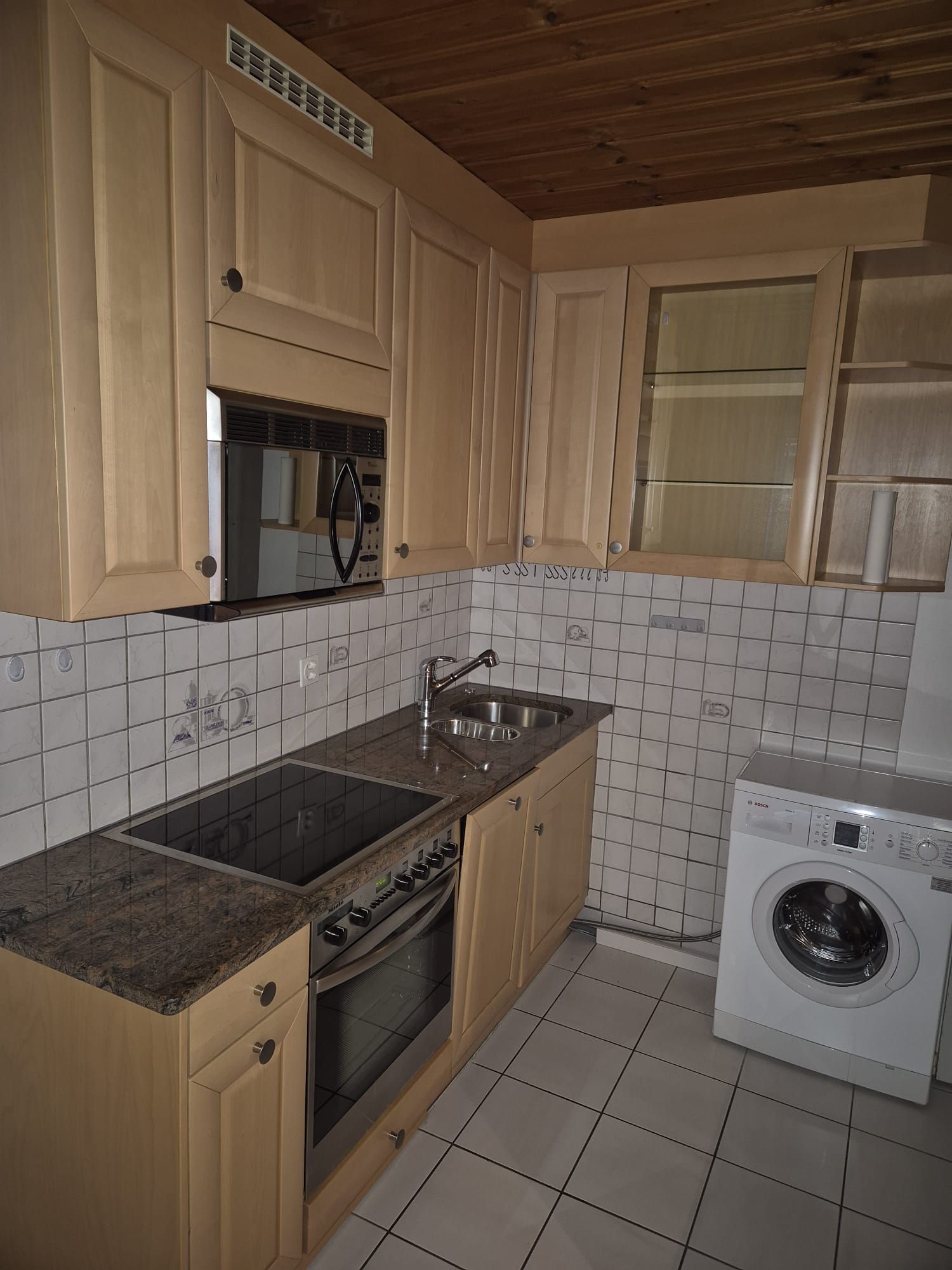Eine Küche mit Holzschränken und einer Waschmaschine