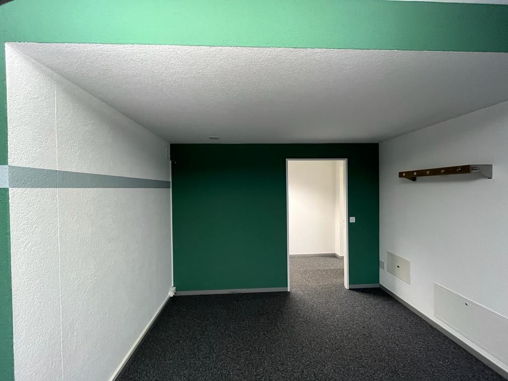 Ein leerer Raum mit grünen Wänden und schwarzem Teppich