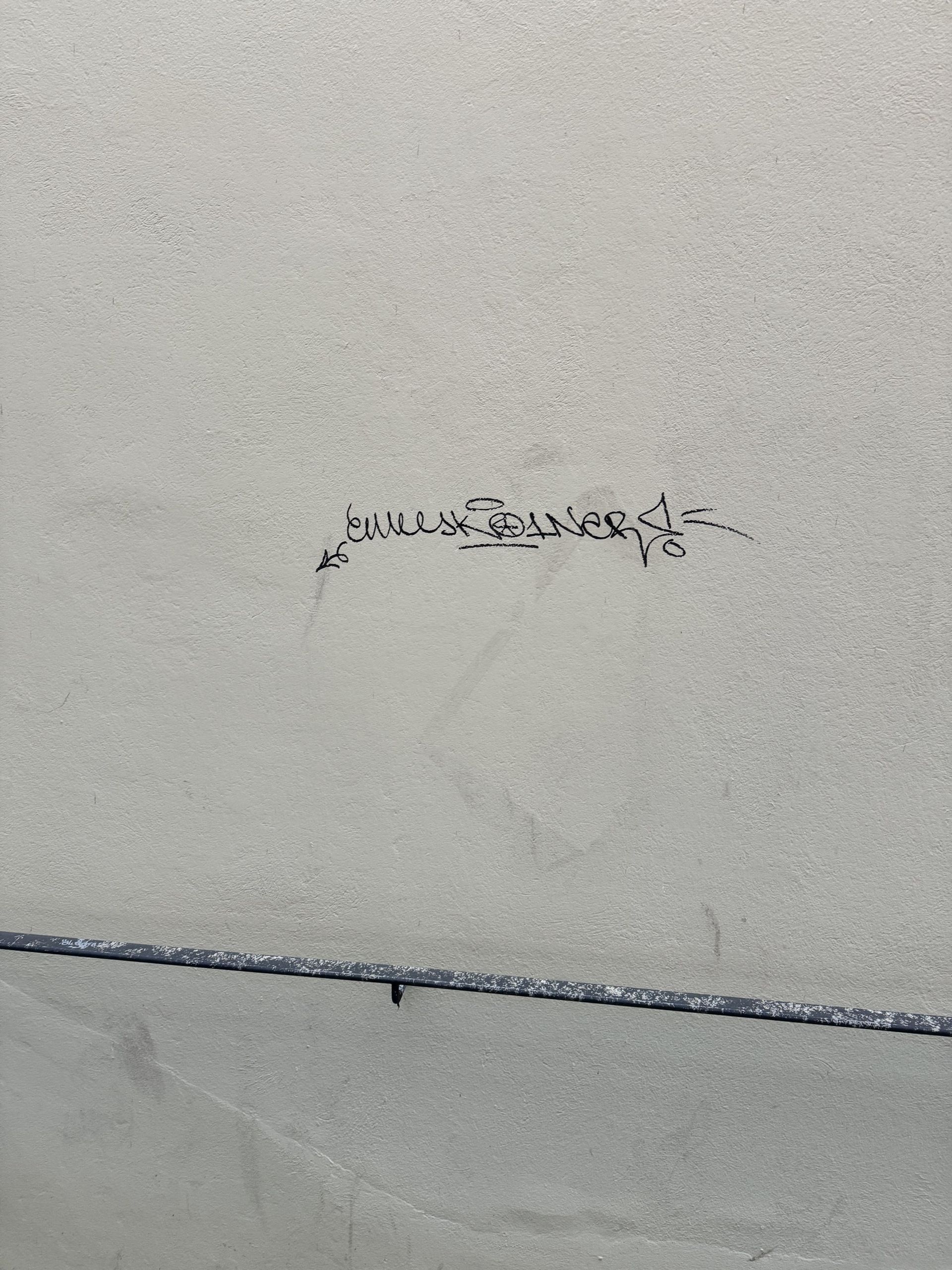 Eine Nahaufnahme einer weißen Wand mit einer Schrift darauf.