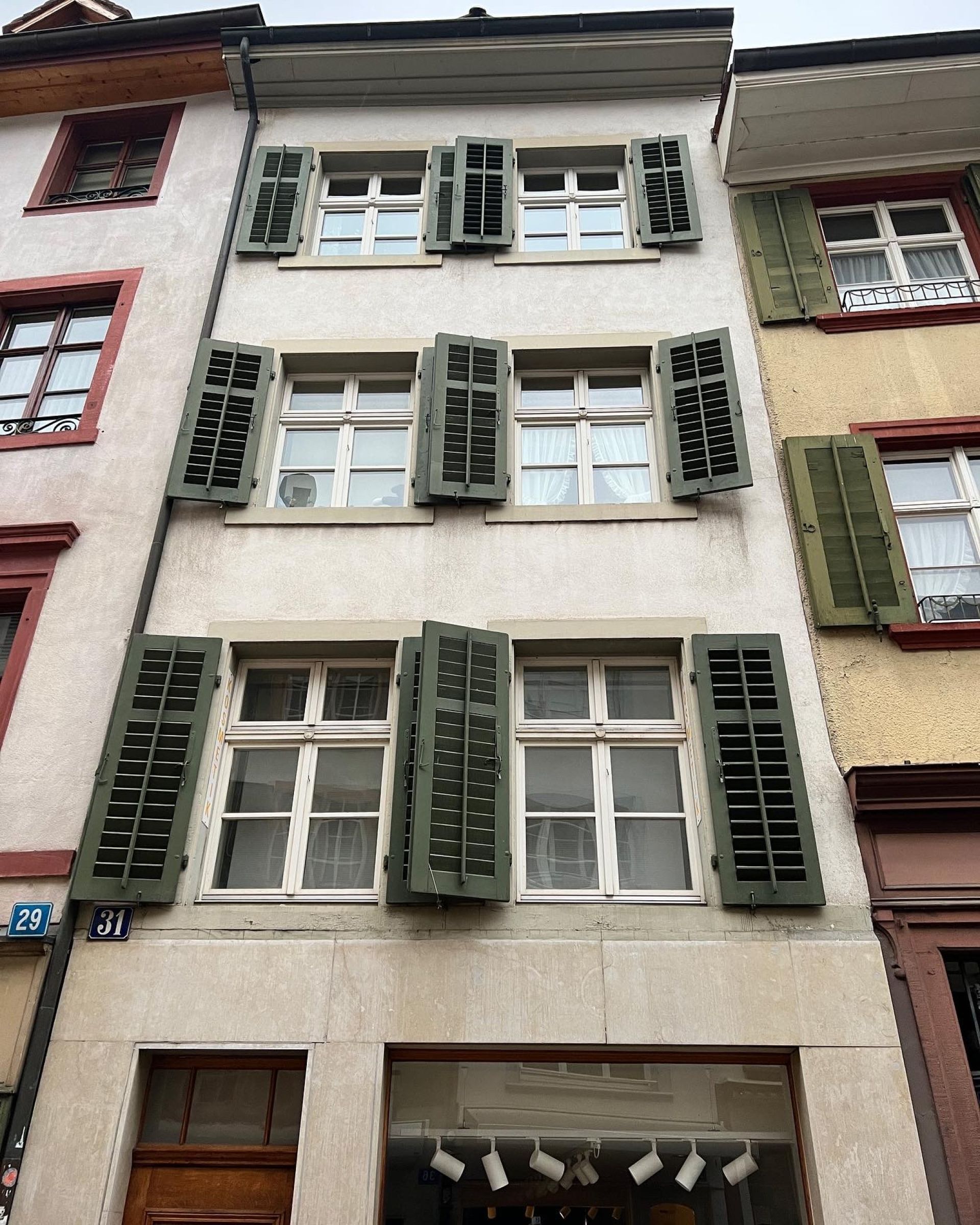 Ein Gebäude mit vielen Fenstern und grünen Fensterläden