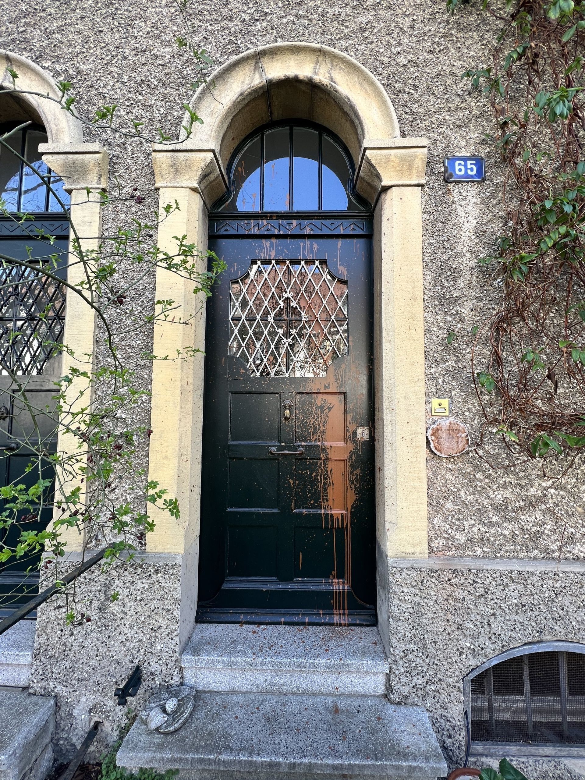 An der Vorderseite eines Gebäudes befindet sich eine schwarze Tür mit einem runden Fenster.