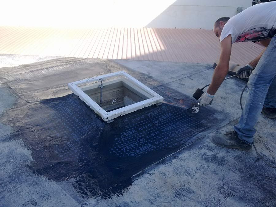 Un hombre está trabajando en un techo con una herramienta.