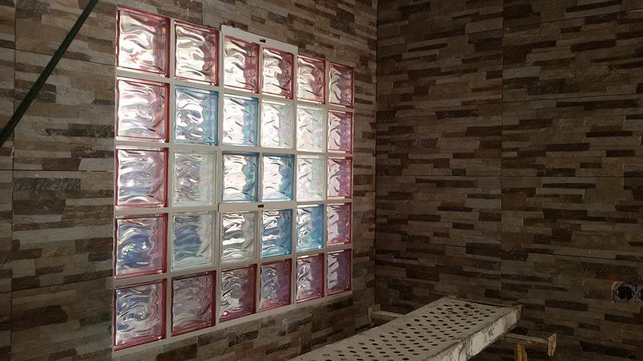 Una habitación con una pared de ladrillos y una ventana hecha de bloques de vidrio.