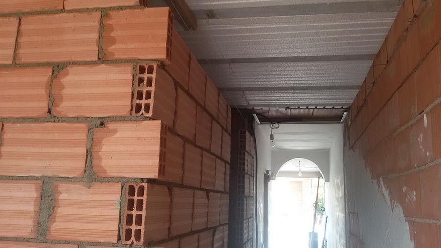 Un largo pasillo con paredes de ladrillo y techo de metal.