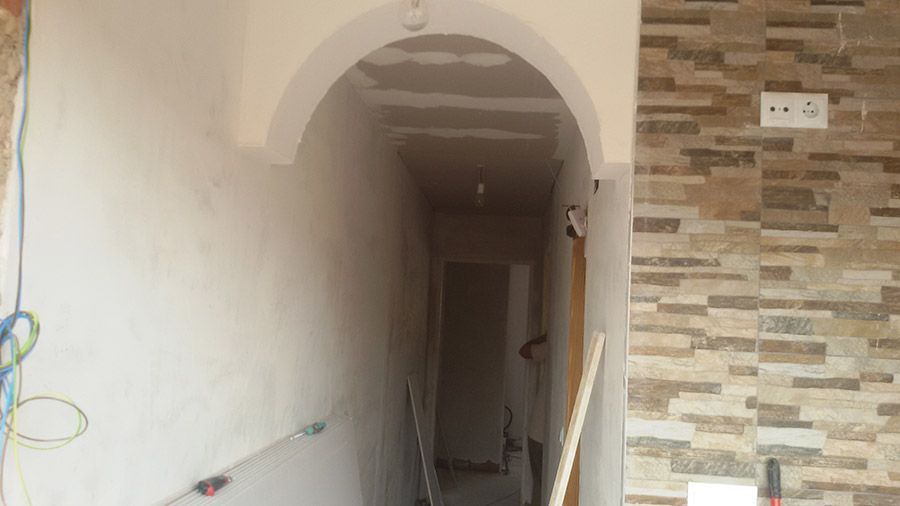 Un pasillo con una pared de piedra y un arco blanco.