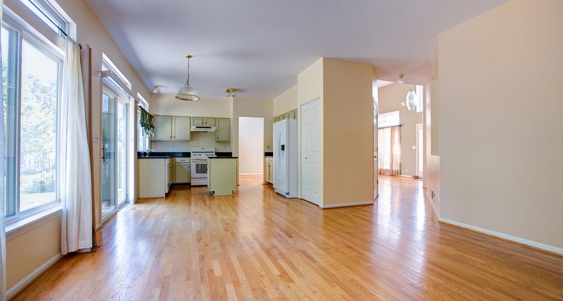 Una gran habitación vacía con pisos de madera y una cocina.