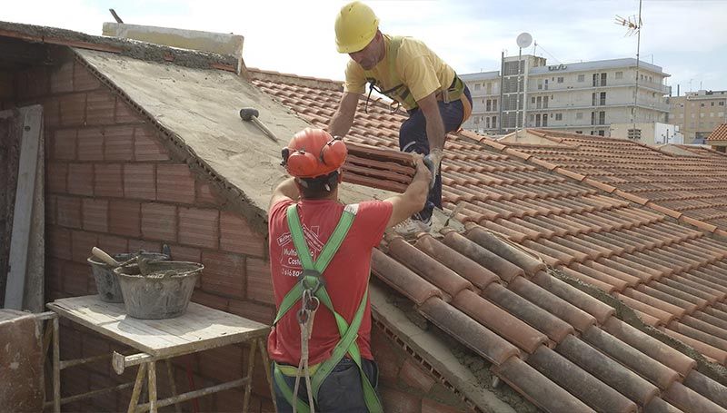 Dos hombres están trabajando en el tejado de un edificio.