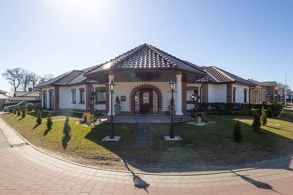 Auf einem üppigen grünen Rasen steht ein großes weißes Haus mit Ziegeldach.