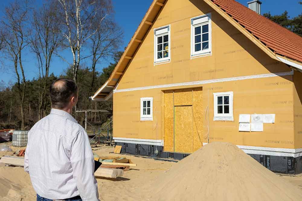 Ein Mann steht vor einem im Bau befindlichen Haus.