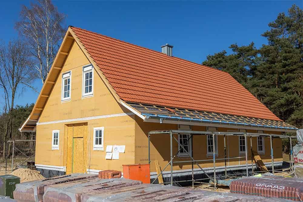 Es wird ein Haus mit einem roten Ziegeldach gebaut.