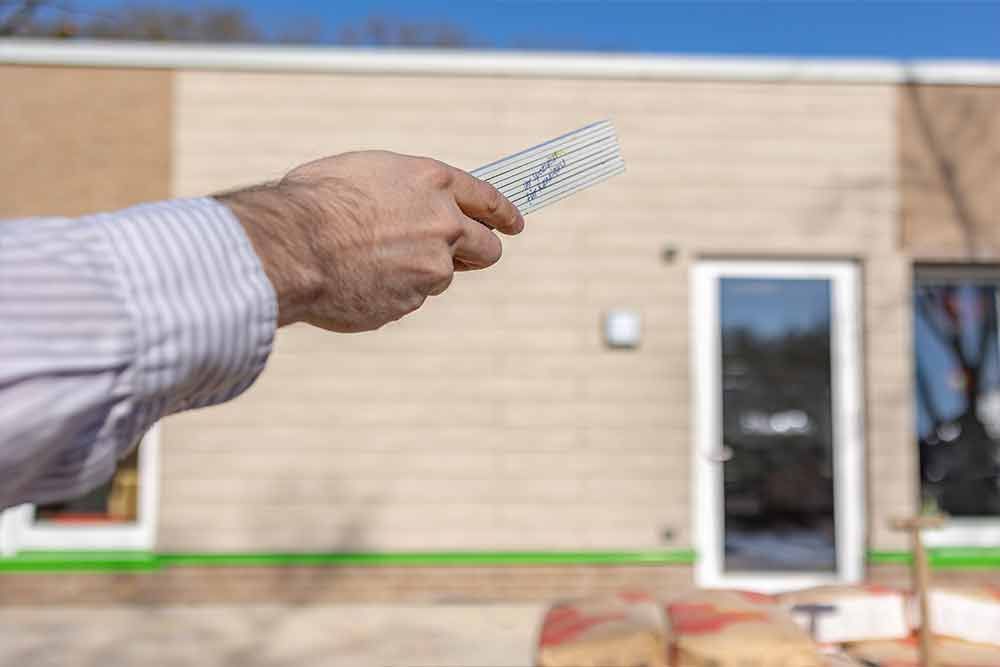 Ein Mann hält eine Fernbedienung vor einem Haus.