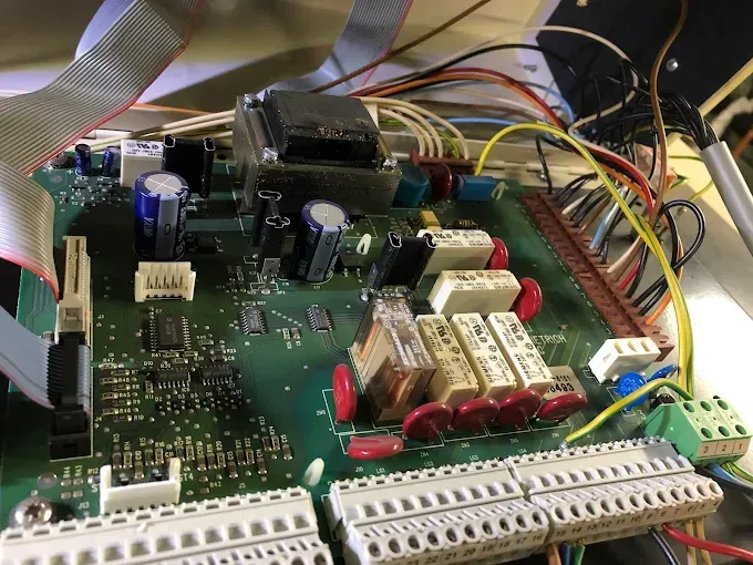 Leiterplatte mit Drähten, Kondensatoren und Steckverbindern in einem offenen Elektronikgerät