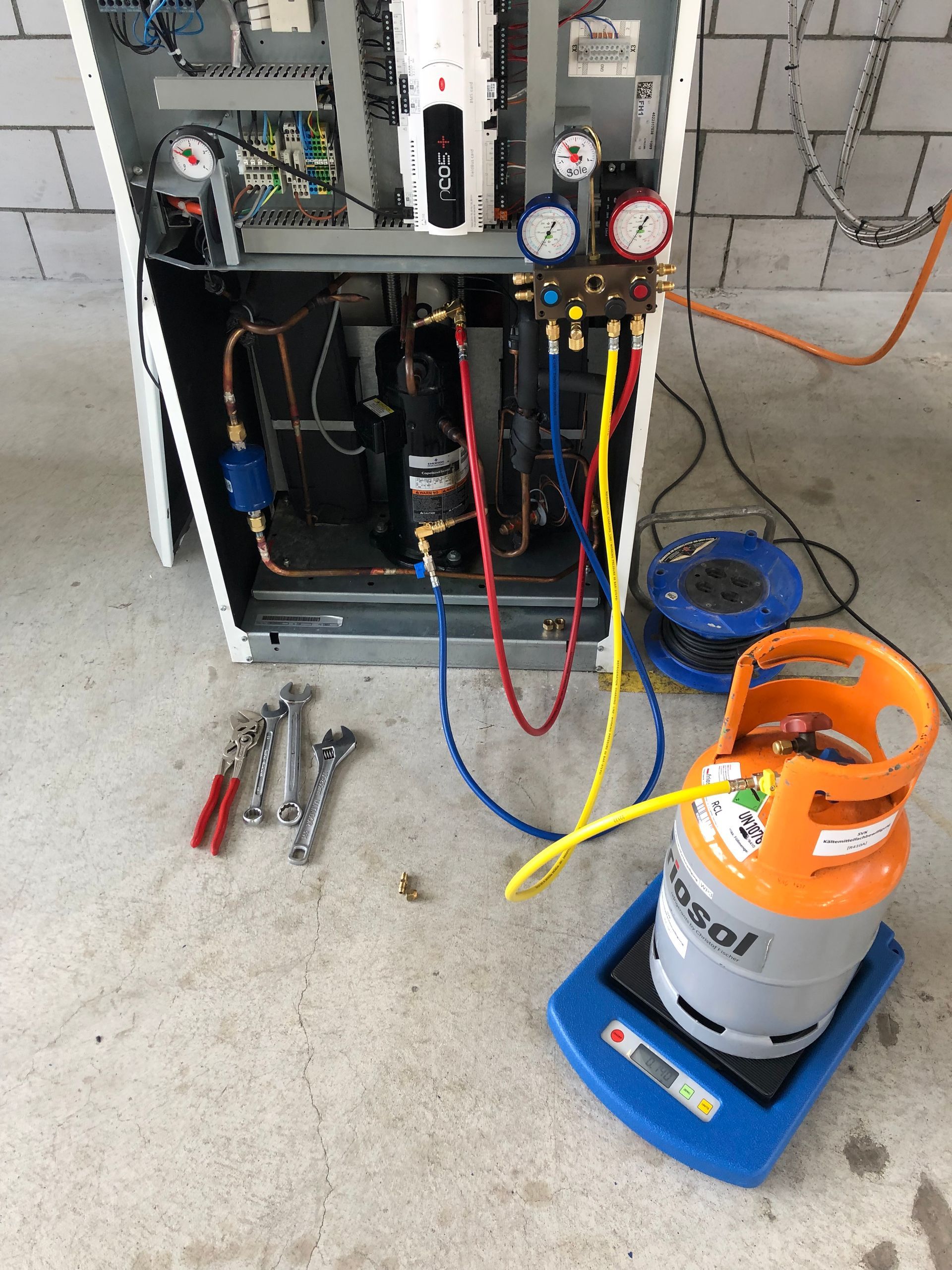 Auf einer grünen Fläche lagen verstreut mechanische Teile und Werkzeuge, darunter eine schwarze Tasche und ein weißes Plastikteil.
