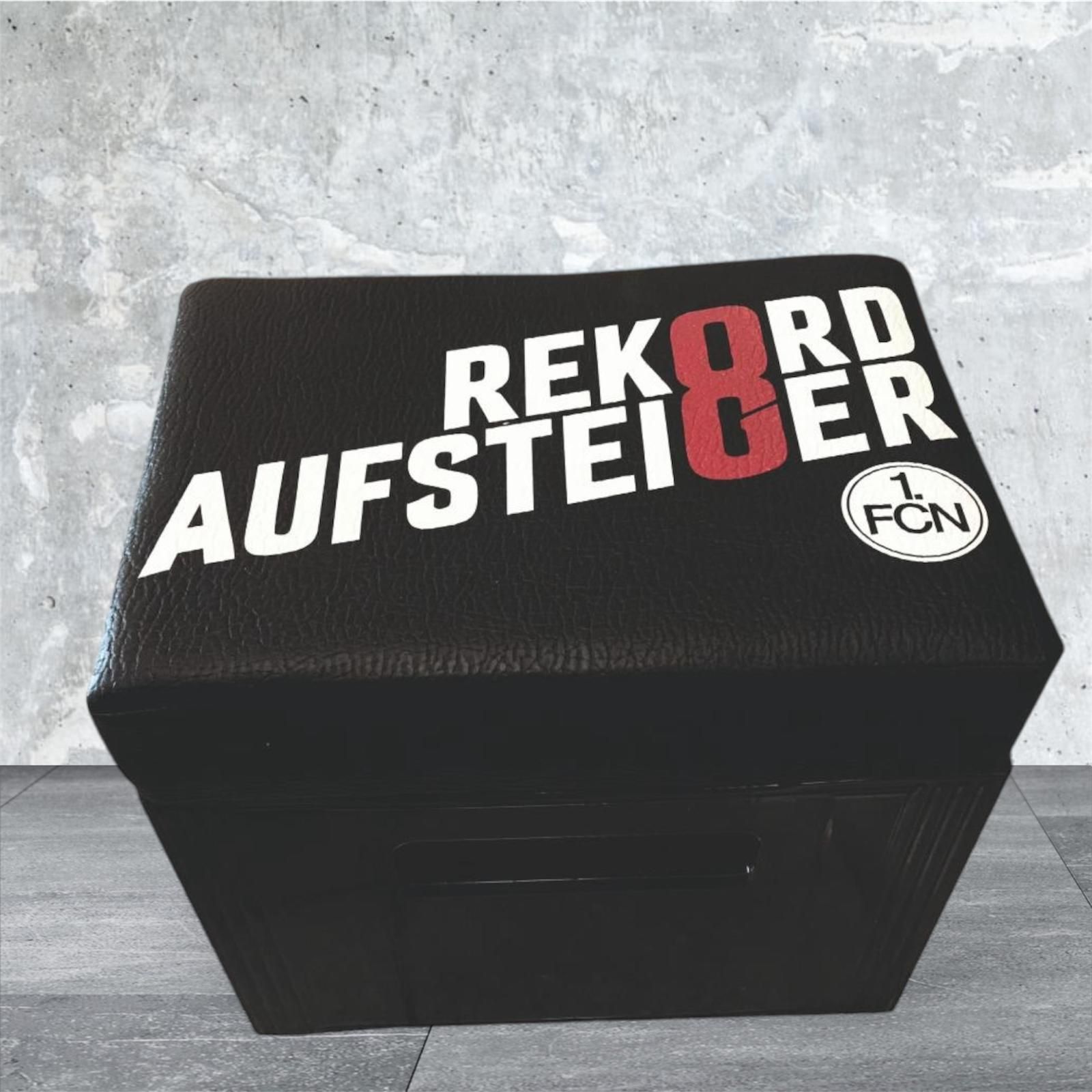 Schwarzer Ottoman mit dem Text „REKORD AUFSTEIGER 8“ in Weiß, Rot und Weiß. „1 FCN“-Logo.