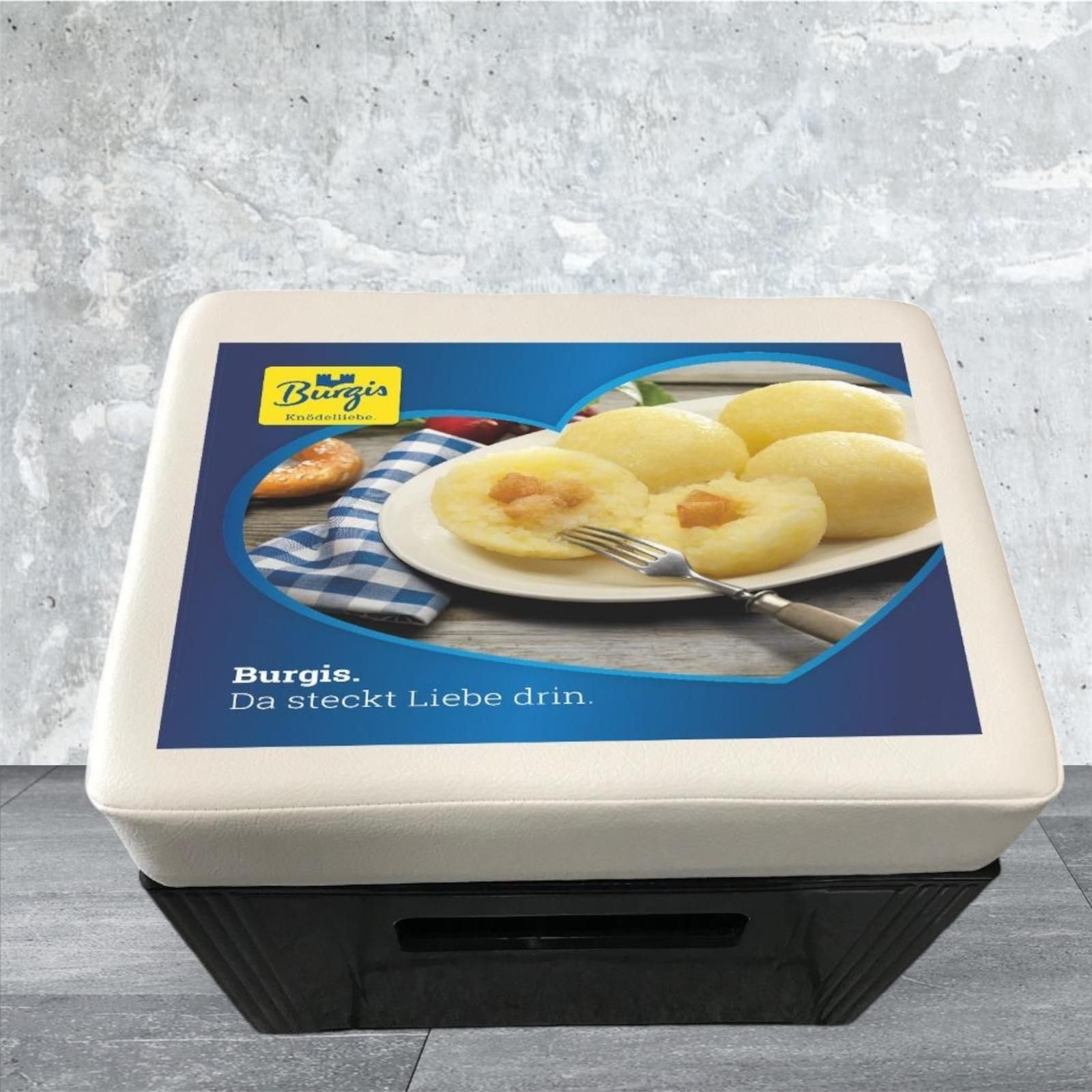 Ein Behälter mit Burgis-Essen mit einem Foto von Kartoffelknödeln in einer Küchenumgebung.