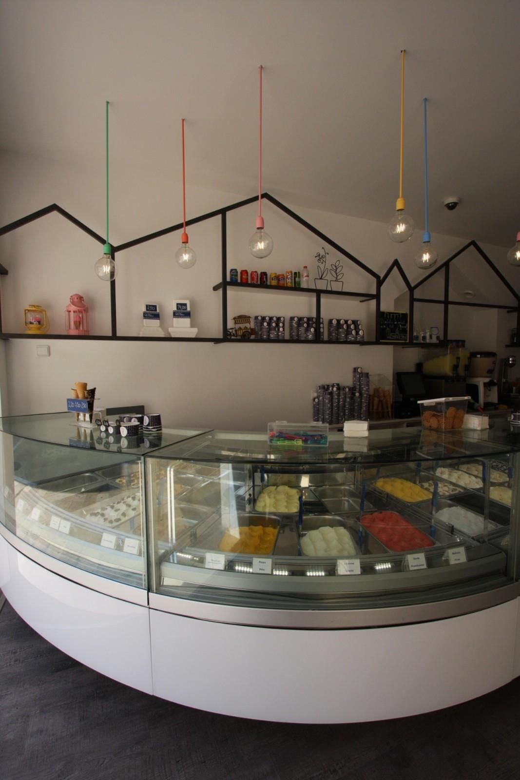 Interior moderno de una pastelería con vitrina de cristal y lámparas colgantes.
