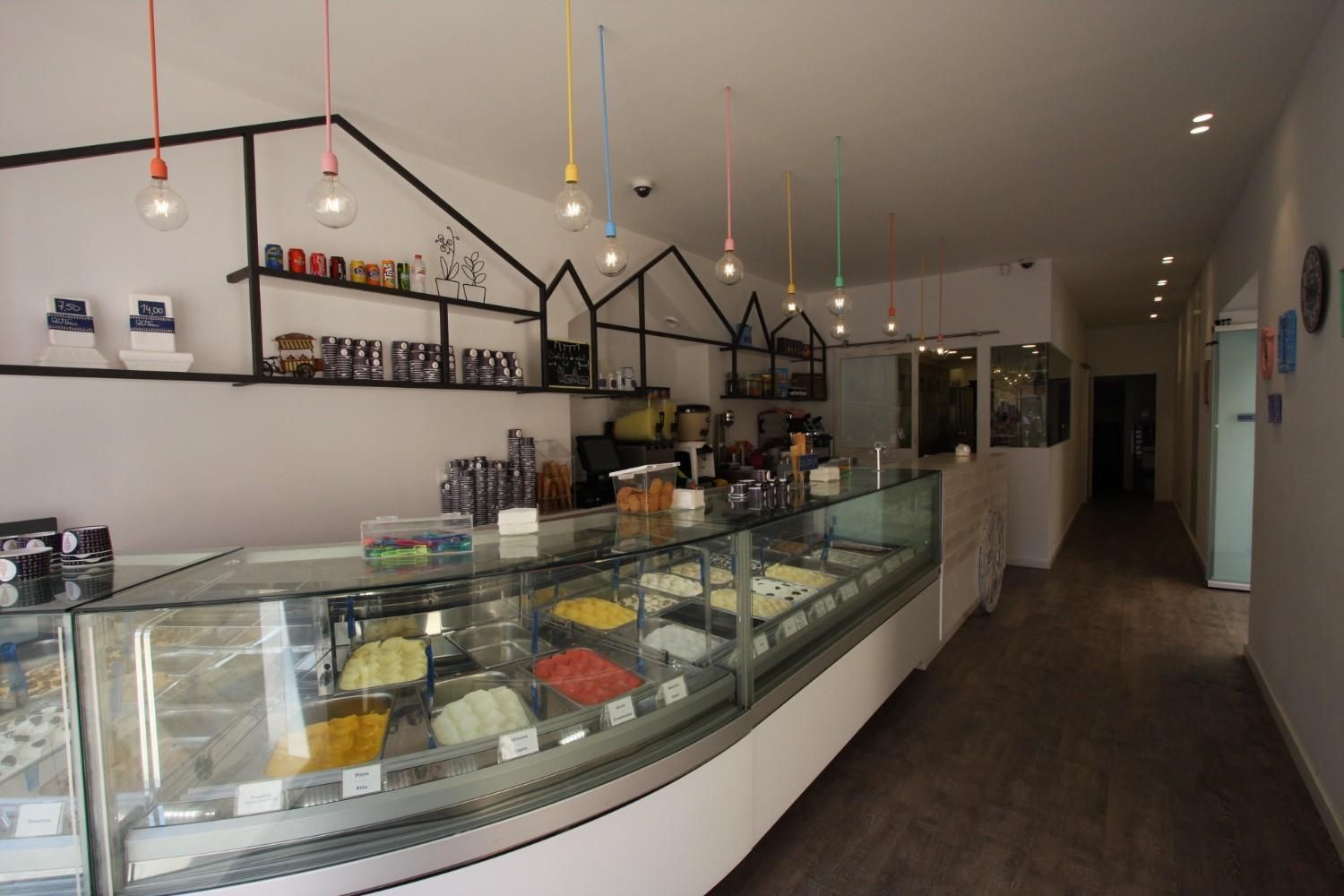 Interior de cafetería moderno con vitrina de pasteles de cristal curvado y lámparas colgantes.