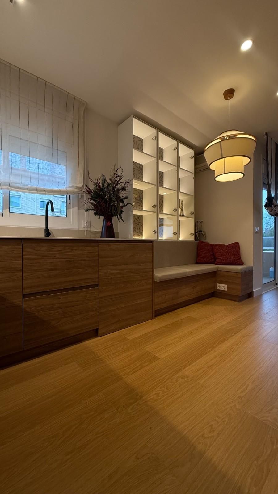 Acogedor recibidor moderno con suelo de madera, estanterías empotradas, banco y lámpara colgante.