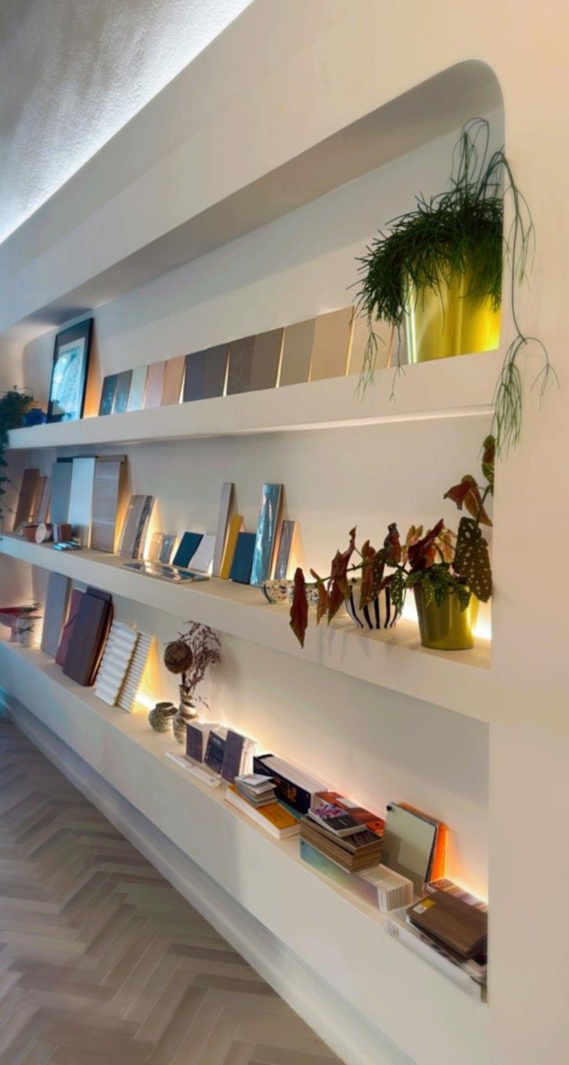 Armarios blancos empotrados con estantes de madera que exhiben una cafetera, tazas, fotos enmarcadas y elementos decorativos.