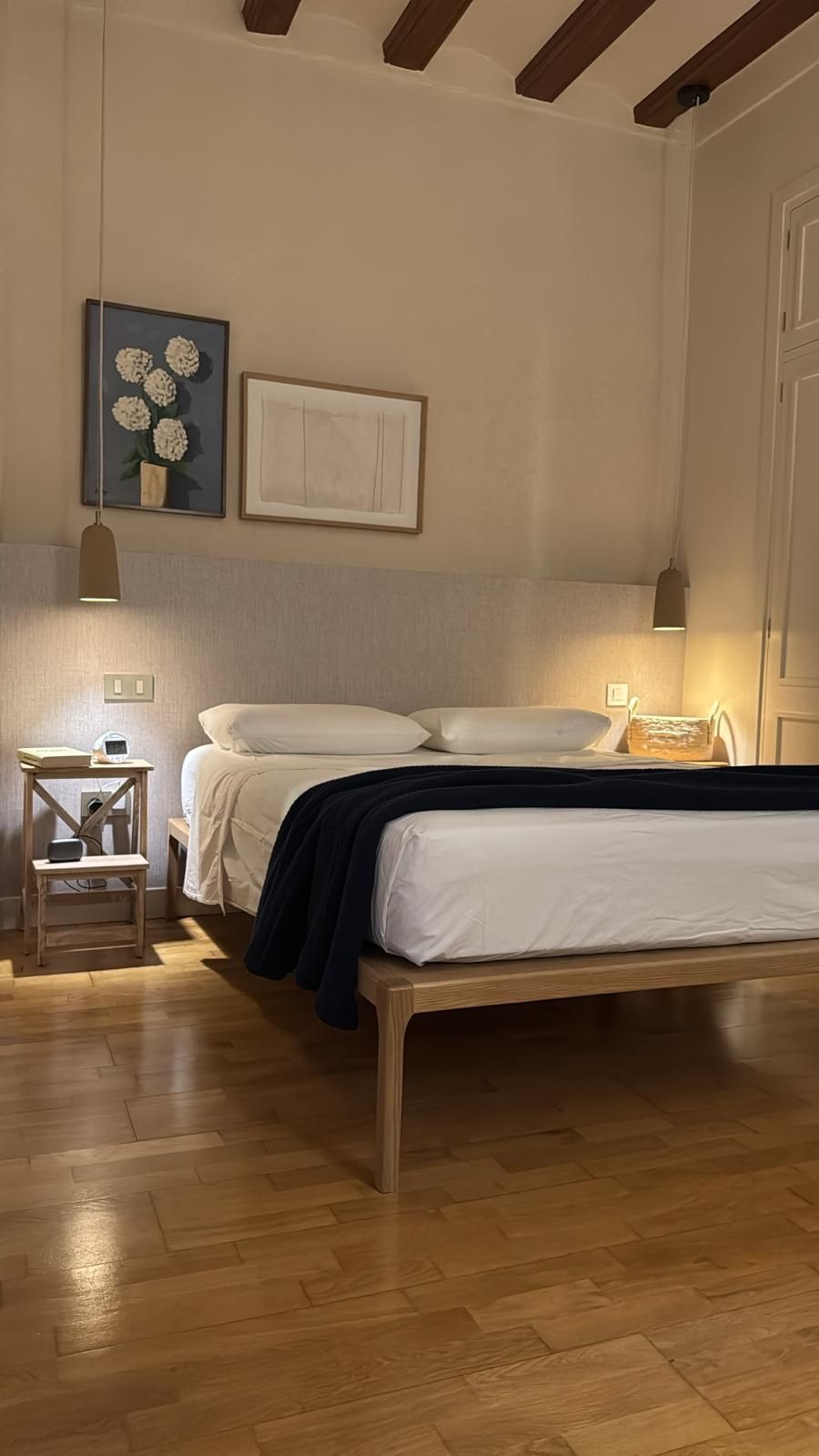 Habitación acogedora con vigas de madera, dos camas individuales, lámparas de noche cálidas y cuadros enmarcados.