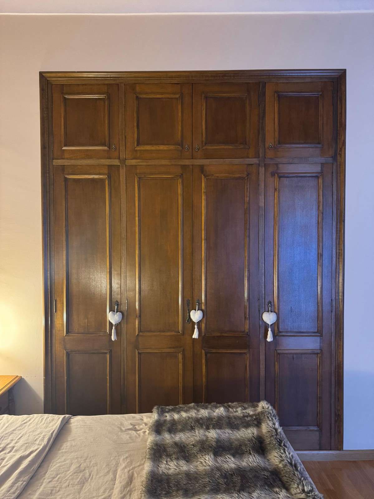 Puertas de armario con paneles de madera en un dormitorio, con una cama en primer plano.