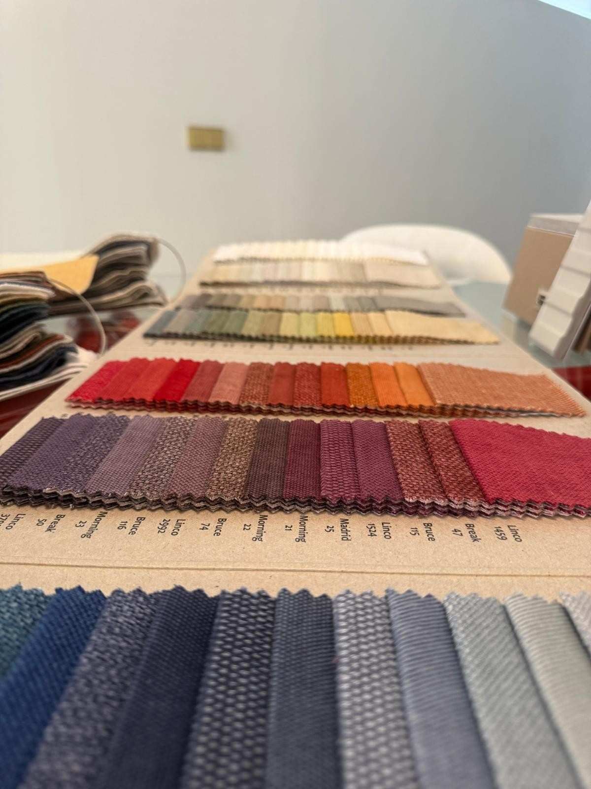 Tableta gráfica, bocetos, muestras de color y láminas de muestra de madera esparcidas por un espacio de trabajo de diseño.
