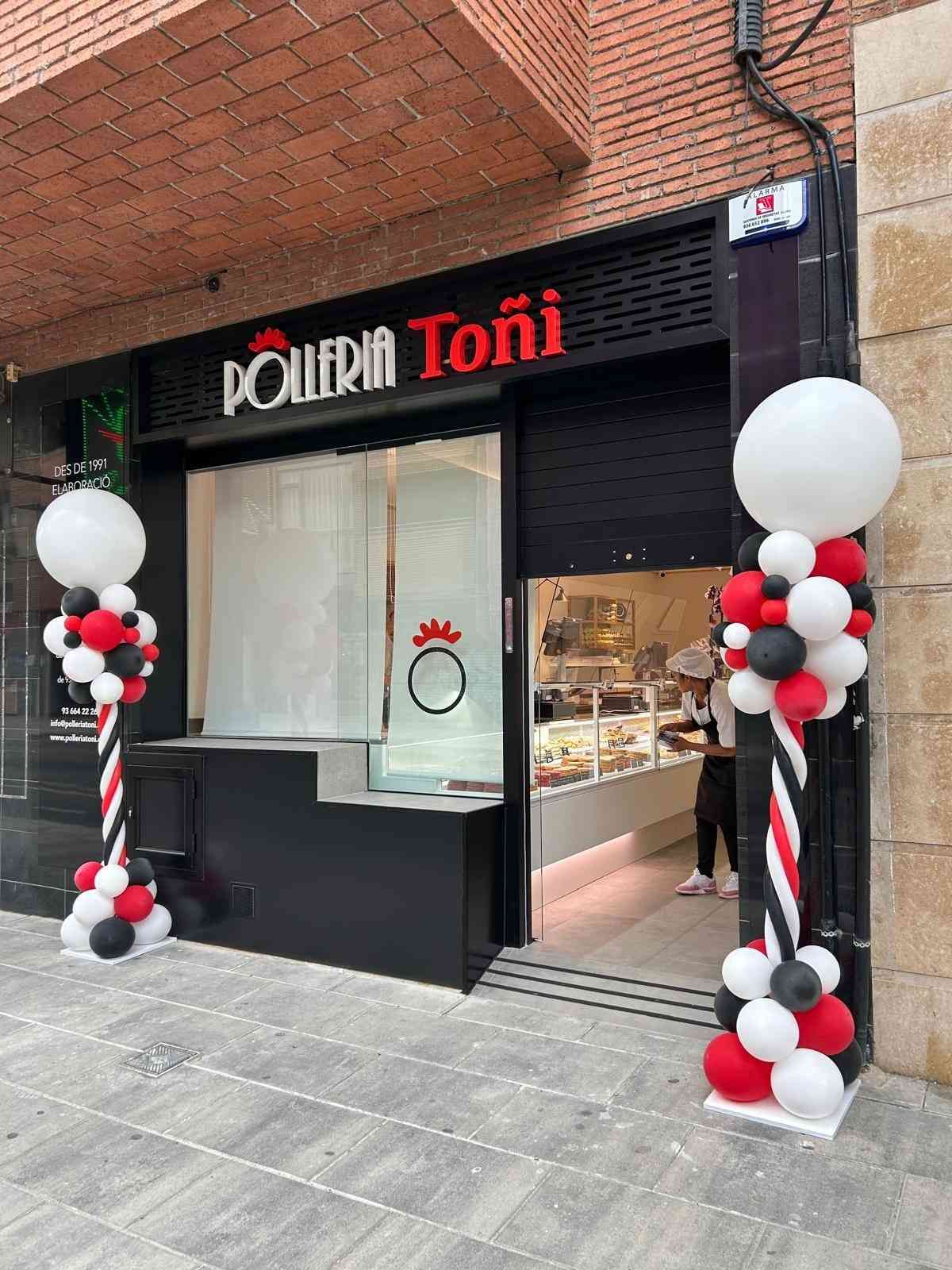 Fachada de la tienda Pollarin Toni con fachada negra, letrero rojo y decoración de globos negros, blancos y rojos en la entrada.