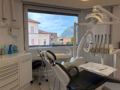 Esame odontoiatrico: bocca aperta, strumenti odontoiatrici per ispezionare i denti, mani con guanti blu.