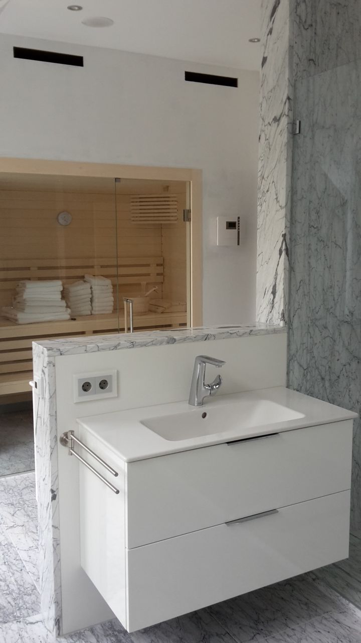 Modernes Badezimmer mit weißem Waschtisch, Waschbecken, Spiegel und Marmorwandpaneelen