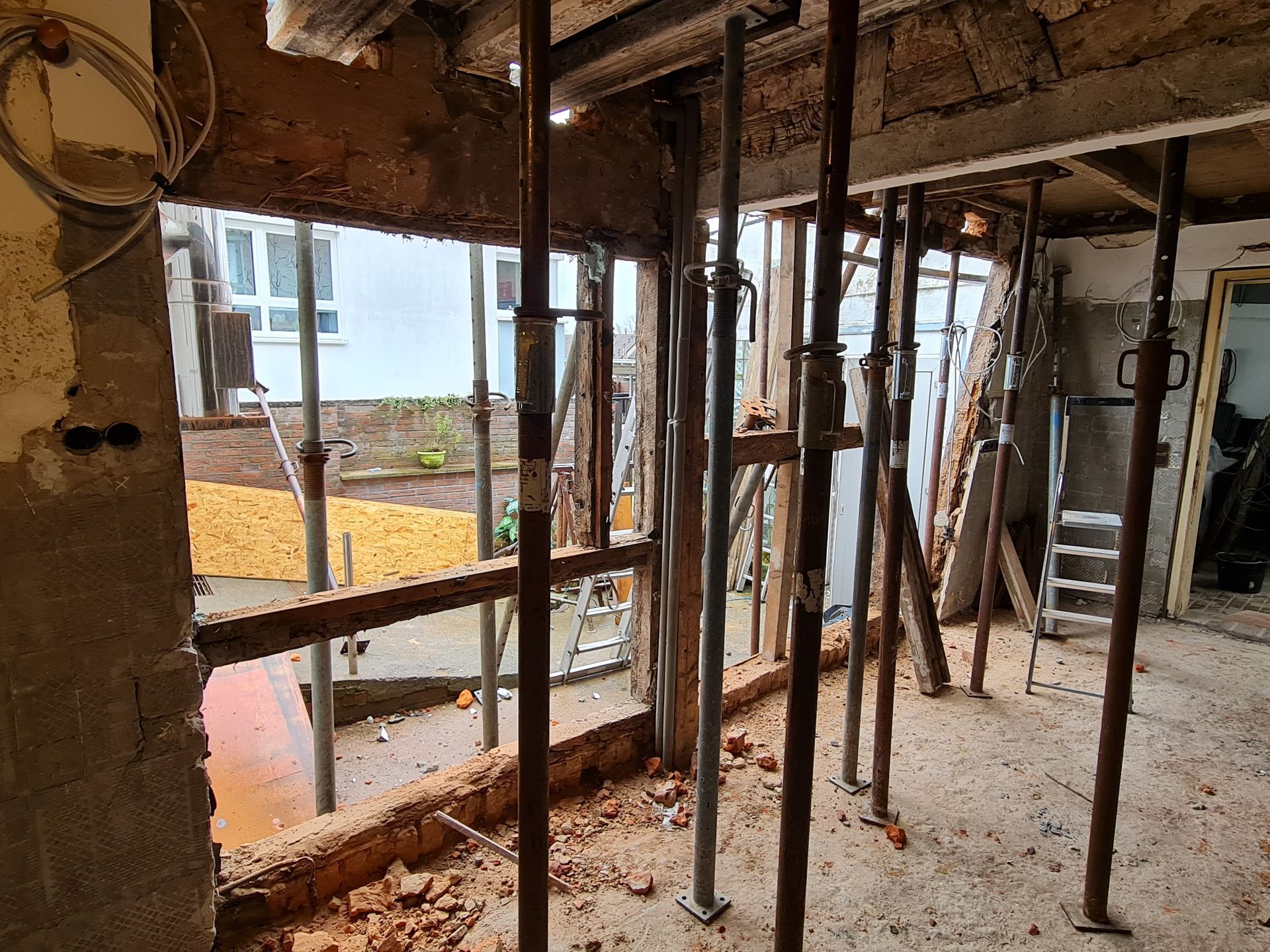 Innenrenovierung mit freiliegenden Deckenbalken, Stützpfeilern und Bauschutt auf dem Boden
