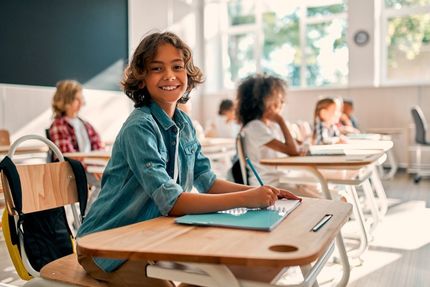 Lächelnder Schüler an seinem Schreibtisch