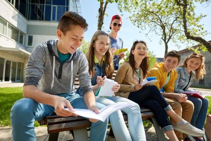 Lächelnde Schüler sitzen auf einer Bank